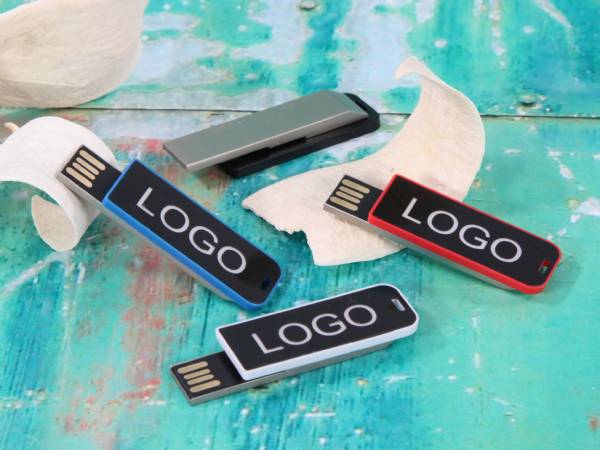 USB-Sticks in Blau, Schwarz und Rot mit Platz für individuelles Logo, auf buntem Untergrund platziert.