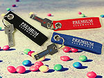 Schlüsselanhänger mit stilisierten USB-Sticks in Rot, Blau und Schwarz, individuell bedruckbar mit dem Logo.