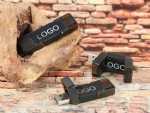 USB-Sticks in schwarzem Gehäuse mit Platz für individuelle Logos, dekorativ auf Holz und Stein präsentiert.