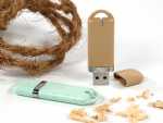 USB-Sticks aus Biokunststoff in braun und mint, umgeben von Naturmaterialien für umweltbewusste Werbung.