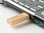 USB-Stick aus Holz, modern und abgerundet, steckt in einem Laptop-Anschluss für einfache Datenübertragung.