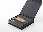 USB-Stick aus Holz in runder Form, elegant verpackt in einer schwarzen Box mit Schaumstoffeinlage.