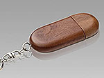 USB-Stick aus dunklem Holz in ovaler Form mit Schlüsselanhänger und Platz für individuelle Logo-Gestaltung.