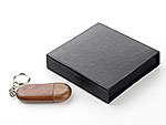 USB-Stick im ovalen, dunkelbraunen Holzdesign, geliefert in einer stilvollen schwarzen Verpackung. Ideal für individuelle Logos.