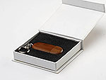 USB-Stick aus Holz in ovaler Form, elegant verpackt in einer weißen Box mit schwarzem Innenfutter.