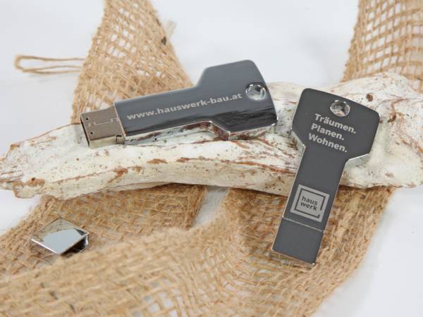 USB-Stick in Form eines Schlüssels mit individuell bedruckbarem Logo-Bereich und eingravierten Slogans.
