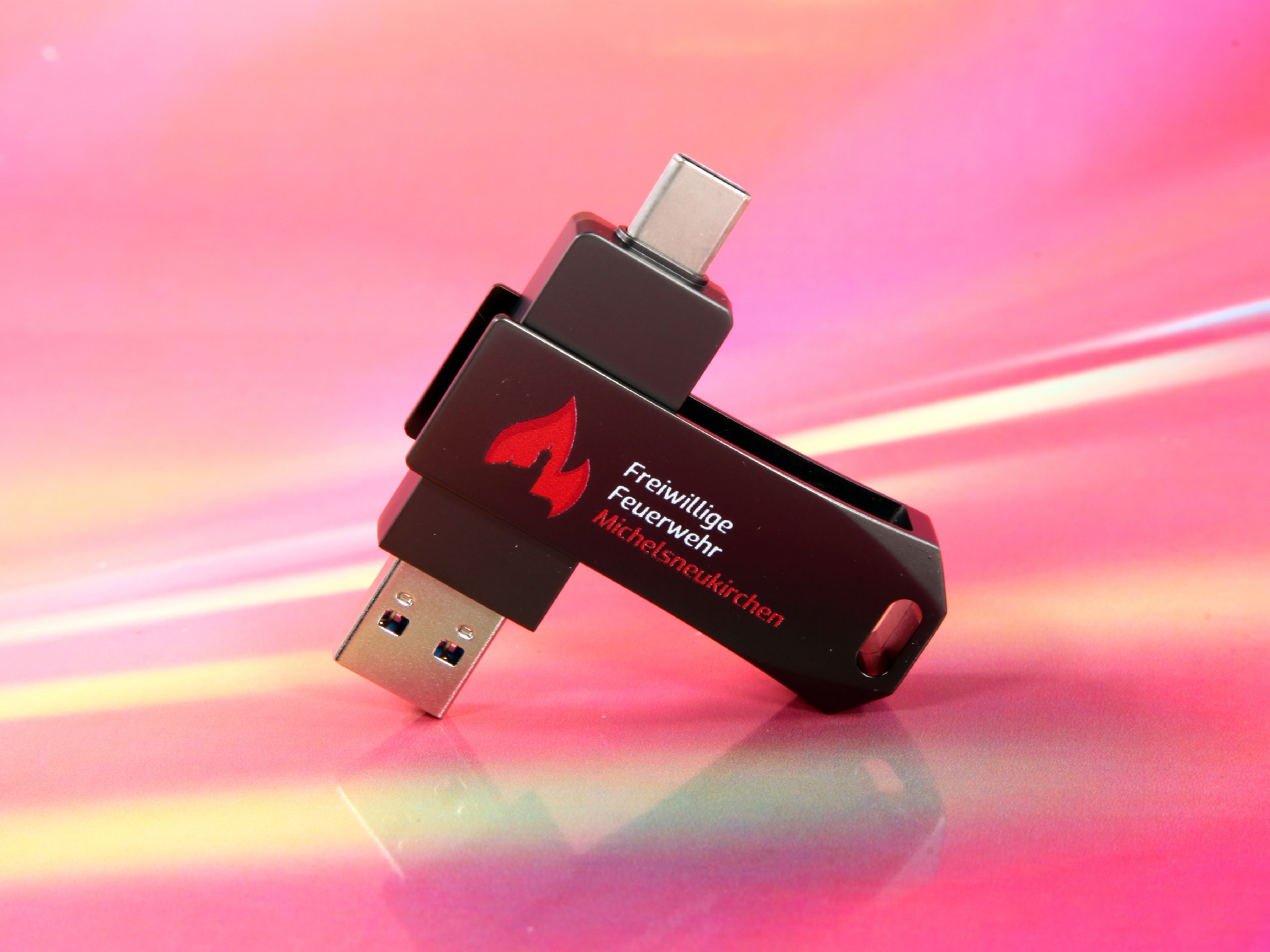 USB-Stick in Schwarz mit rotem Logo der Freiwilligen Feuerwehr, drehbar und kompakt für einfache Handhabung.