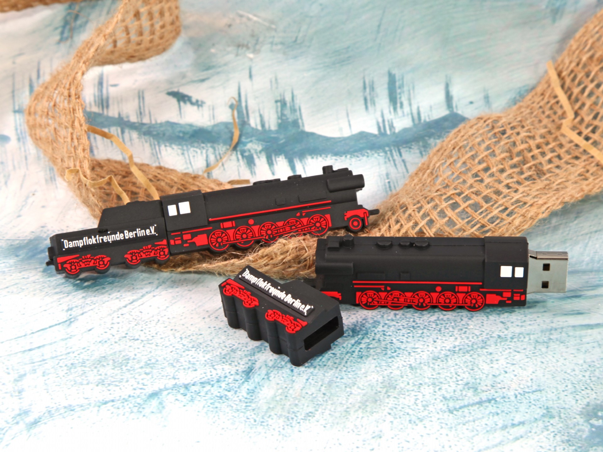 USB-Stick im Lokomotiv-Design mit rotem und schwarzem Gehäuse, ideal für individuelle Markenpräsentationen.